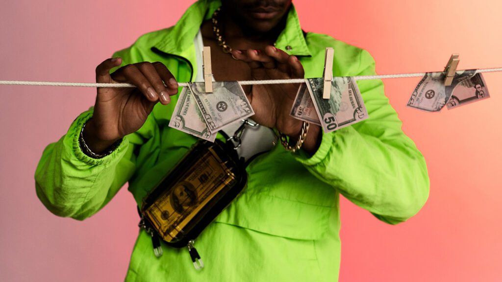Mann in grünem Outfit hängt Geldscheine auf eine Wäscheleine auf.