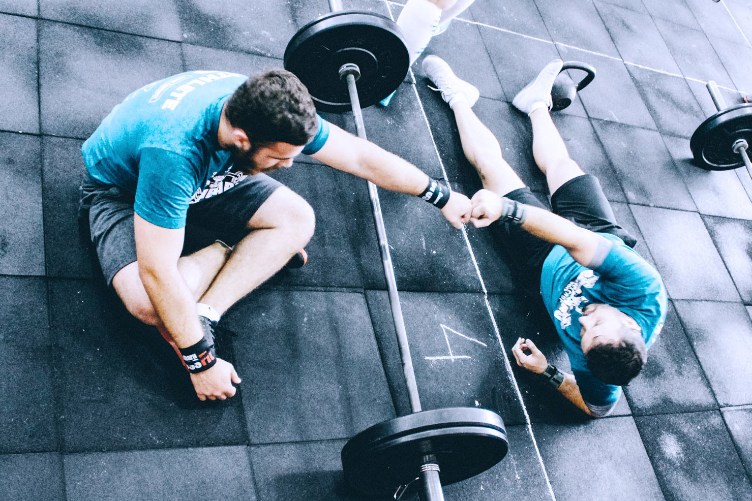 Zwei sportliche Männer im Fitnessstudio geben sich gegenseitig ein Fistbump, beim Gewichteheben